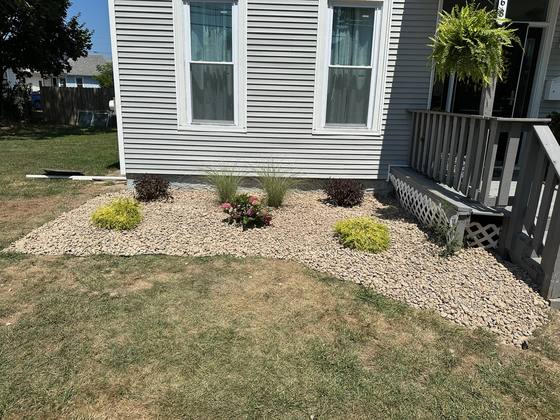 Finished river rock landscape bed with new shrubs and perennials in Akron, NY