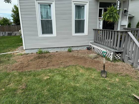 Bare dirt front landscape bed before installation at a home in Akron, NY
