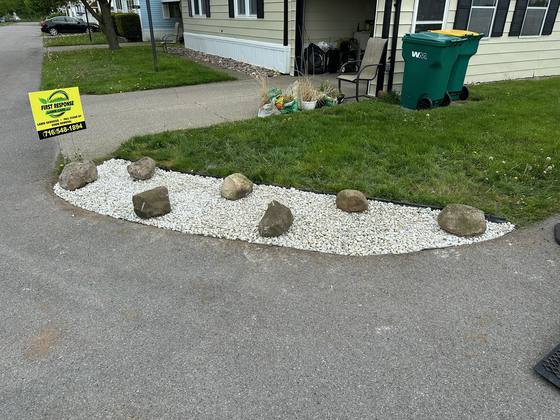 Finished white stone bed with fieldstone boulders along a driveway in Akron, NY